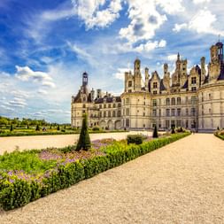 Schloss Chambord, ein Renaissance-Schloss mit markanten Türmen, von französischen Gärten mit Kieswegen und Hecken aus gesehen.