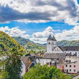 Panoramablick auf Treis-Karden mit der St. Castor Kirche mit zwei Türmen, umgeben von grünen Hügeln entlang der Mosel.