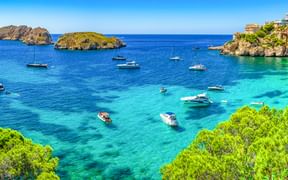 Panoramablick auf die Bucht von Santa Ponça auf Mallorca mit türkisfarbenem Wasser, ankernden Booten, Felseninseln und Küstengebäuden auf Klippen.