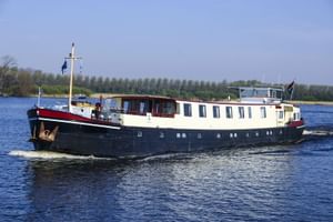 MS Lena Maria, ein Passagierschiff mit dunkelblauem Rumpf und weißem Aufbau, fährt auf einem Fluss mit Bäumen am Ufer.