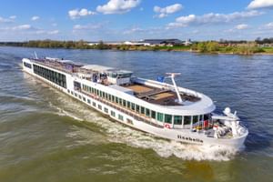 Weißes Flusskreuzfahrtschiff MS Lisabelle fährt auf einem breiten Fluss unter blauem Himmel mit Wolken. Das moderne Schiff hat mehrere Decks und Panoramafenster.