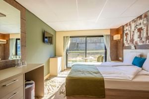 Moderne Schiffskabine auf der MS Lisabelle mit Doppelbett, olivgrünen Akzenten, Schreibtisch, TV und großem Fenster mit Vorhängen zum Deck.