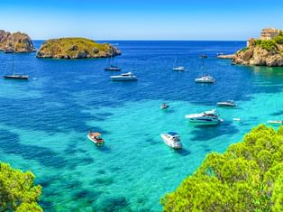 Panoramablick auf die Bucht von Santa Ponça auf Mallorca mit türkisfarbenem Wasser, ankernden Booten, Felseninseln und Küstengebäuden auf Klippen.