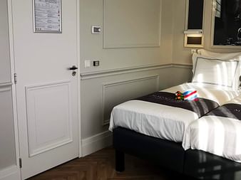 Modernes Suite-Schlafzimmer auf der MS Magnifique IV mit Doppelbett, weißer Bettwäsche, Holzboden, getäfelten Wänden und Kunstwerk über dem Kopfteil.