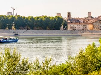 Blau-weißes Passagierschiff MS Caprice auf der Rhône mit historischen Stadtgebäuden und Kirchtürmen entlang des Ufers.