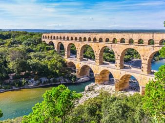 Pont du Gard antikes römisches Aquädukt mit drei Bogenreihen über dem Gardon-Fluss bei Remoulins, umgeben von grüner Vegetation.