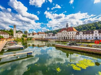 Hafenbecken in Bad Karlshafen mit Booten, weißem Barock-Rathaus mit rotem Dach und historischen Gebäuden, die sich im ruhigen Wasser spiegeln.