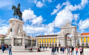 Praça do Comércio in Lissabon mit Reiterstatue und Arco da Rua Augusta. Gelbe Gebäude rahmen den Platz, Touristen unter blauem Himmel.