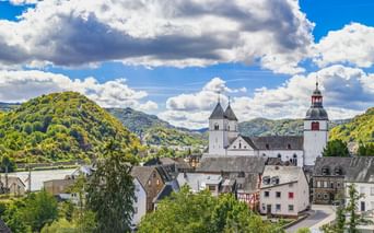 Panoramablick auf das Dorf Treis-Karden an der Mosel mit der St. Castor Kirche mit weißem Turm und rot bedachtem Glockenturm.