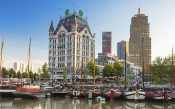 Alter Hafen Rotterdam mit historischen Booten im Vordergrund. Das Witte Huis mit seinem markanten Turm steht prominent zwischen modernen Hochhäusern.