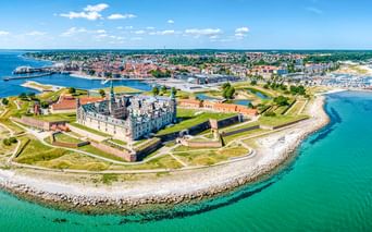 Luftaufnahme von Schloss Kronborg auf einer Halbinsel in Helsingør, Dänemark. Die Renaissancefestung ist von grünen Wällen und blauem Meer umgeben.