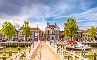 Weiße hölzerne Zugbrücke Raadhuisbrug führt zu historischen Gebäuden im Hafen von Harlingen. Traditionelle niederländische Häuser und Boote säumen das Ufer.