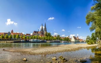 Panoramablick auf Regensburgs historische Skyline mit den Domtürmen über bunten Gebäuden entlang der Donau.