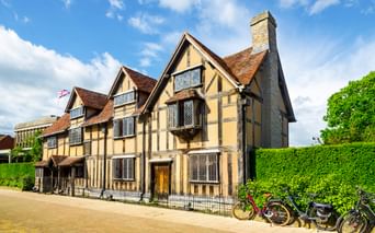 Historisches Tudor-Fachwerkhaus mit cremefarbenen Wänden und dunklen Balken in Stratford-upon-Avon, William Shakespeares Geburtshaus. Fahrräder davor.