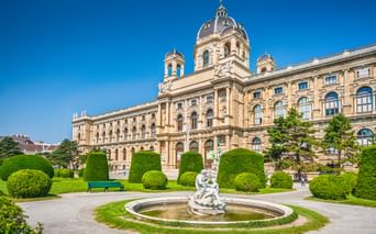 Naturhistorisches Museum Wien mit prachtvoller Barockfassade, zentraler Kuppel und gepflegtem Park mit Brunnen und Formschnitthecken.