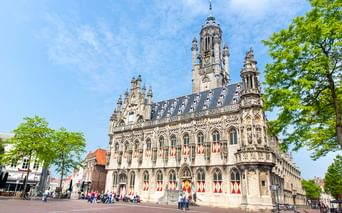 Das prächtige Stadhuis Rathaus in Middelburg mit gotischer Fassade, verzierten Türmen und rot-weißen Fensterläden. Besucher auf dem Platz.