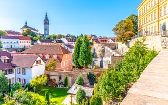 Panoramablick auf die Altstadt von Litoměřice mit bunten Gebäuden, Kirchturm und terrassierten Gärten unter blauem Himmel.
