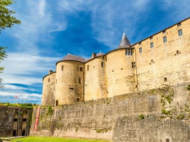 Burg Sedan mit runden Türmen und hohen Steinmauern unter blauem Himmel. Massive Festungsmauern umgeben die mittelalterliche Festung.