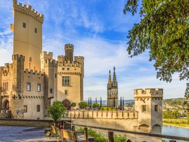 Schloss Stolzenfels castle with yellow walls, crenellated towers, and Gothic chapel spires overlooking the Rhine River near Koblenz.