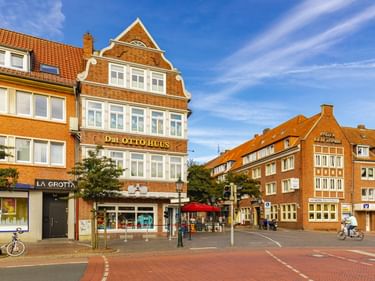 Rotes Backsteingebäude Otto Huus mit weißer Giebelfassade in Emden. Das historische Gebäude hat Geschäfte im Erdgeschoss und einen Fußgängerplatz.