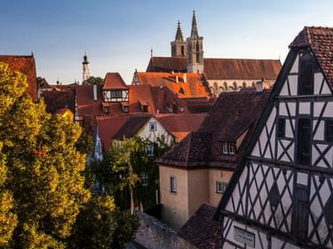 Mittelalterliche Stadt Rothenburg ob der Tauber mit Fachwerkhäusern, roten Ziegeldächern und Kirchtürmen unter blauem Himmel im Herbst.
