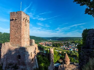 Steinturm und Mauern der Burgruine Wertheim in Bayern. Blick auf die Stadt Wertheim mit bewaldeten Hügeln im Hintergrund.
