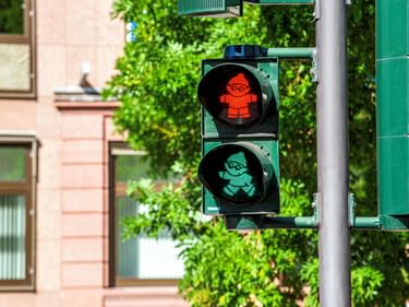 Fußgängerampel in Mainz mit roten und grünen Mainzelmännchen-Figuren. Das rote Stoppsignal zeigt eine stehende Figur, grün eine gehende.
