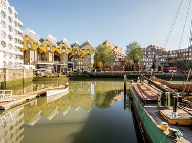 Historischer Oude Haven Hafen in Rotterdam mit ikonischen gelben Kubushäusern, traditionellen Booten am Kai und modernen Gebäuden.