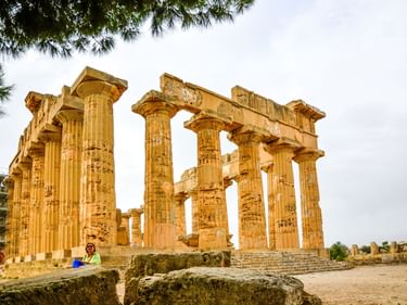 Ruinen eines antiken griechischen Tempels in Selinunte mit hohen dorischen Säulen und teilweisem Gebälk unter bewölktem Himmel.
