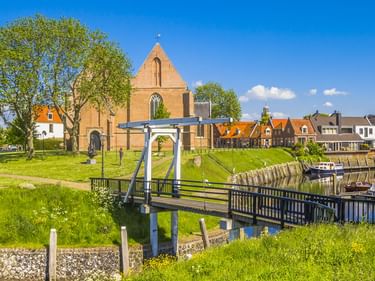 Weiße Zugbrücke über Kanal zum Binnenhafen Vollenhove mit Booten, historischer Kirche und traditionellen niederländischen Häusern.