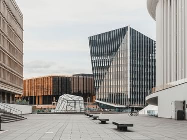 Moderner Platz in Luxemburg mit markanten eckigen Glasgebäuden, darunter der Europäische Gerichtshof und die Philharmonie unter bewölktem Himmel.