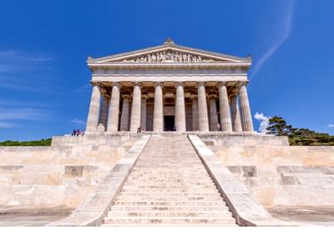 Gedenkstätte Walhalla mit neoklassizistischer griechischer Tempelfassade, dorischen Säulen und dreieckigem Giebel, erreichbar über breite Steintreppe.