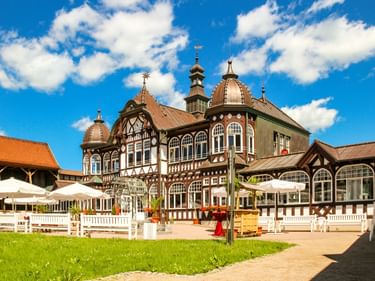 Historisches Fachwerkgebäude mit verzierten Kuppeln und Türmen in Bad Salzungen, mit weißem Außenbereich auf grüner Wiese unter blauem Himmel.