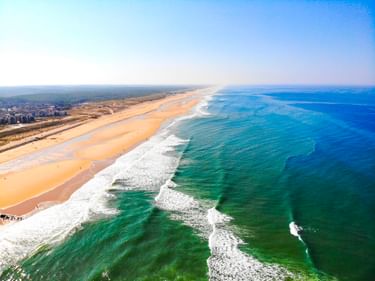 Luftaufnahme des Strandes von Lacanau in Frankreich mit langer Sandküste, weißen Wellen und dem Atlantischen Ozean.
