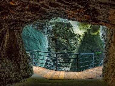 Hölzerne Aussichtsplattform mit Metallgeländer in der Aareschlucht bei Meiringen, mit dramatischen Felswänden und natürlichem Licht.