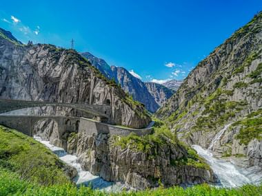 Historische Steinbogenbrücke Teufelsbrücke über einer Schlucht bei Andermatt mit rauschenden Fluss und steilen Felswänden.