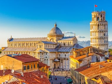 Luftaufnahme der Piazza dei Miracoli in Pisa mit dem berühmten Schiefen Turm und Dom mit weißen Marmorfassaden, umgeben von Terrakottadächern.