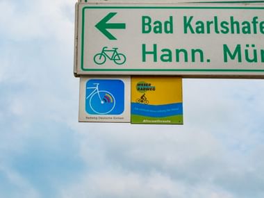 Radweg-Wegweiser nach Bad Karlshafen und Hann. Münd mit Fahrradsymbol und Routenmarkierungen für den Weser-Radweg.