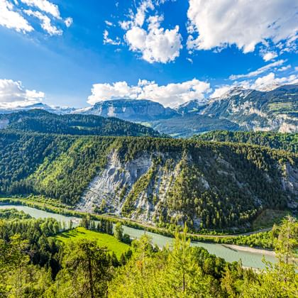 Luftaufnahme der Rheinschlucht in der Schweiz mit türkisfarbenem Fluss, der sich durch bewaldete Berge und weiße Kalksteinfelsen schlängelt.