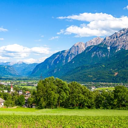 Grüne Wiese im Vordergrund mit Blick auf Lienz und das Tal, umgeben von den markanten Gipfeln der Lienzer Dolomiten unter blauem Himmel.