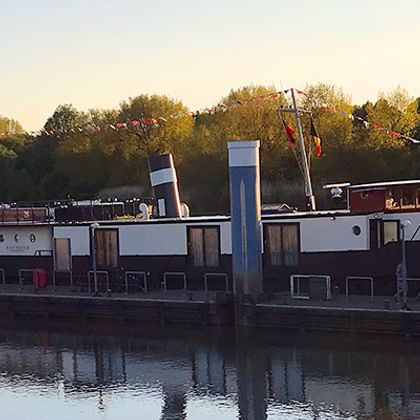 MS Magnifique III liegt bei Sonnenuntergang auf ruhigem Wasser. Das Flusskreuzfahrtschiff hat einen dunklen Rumpf und weiße Oberdecks.