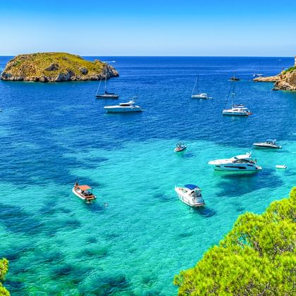 Panoramablick auf die Bucht von Santa Ponça auf Mallorca mit türkisfarbenem Wasser, ankernden Booten, Felseninseln und Küstengebäuden auf Klippen.
