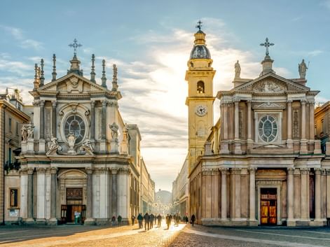 Piazza San Carlo in Turin mit barocken Zwillingskirchen an einer zentralen Straße. Ein goldener Glockenturm erhebt sich zwischen ihnen.