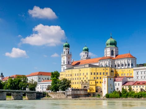 Passau old town with St. Stephen's Cathedral featuring green onion domes along the Inn river. Colorful historic buildings line the waterfront.