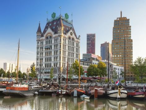 Alter Hafen Rotterdam mit historischen Booten im Vordergrund. Das Witte Huis mit seinem markanten Turm steht prominent zwischen modernen Hochhäusern.
