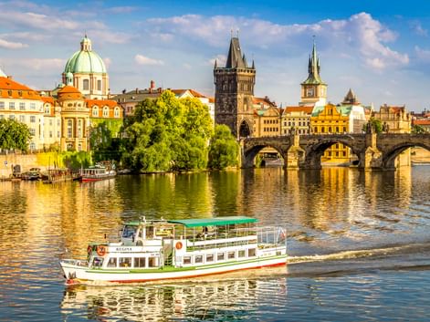 Touristenboot auf der Moldau mit Karlsbrücke und Prager Altstadt mit bunten Gebäuden, Kirchenkuppeln und Türmen.