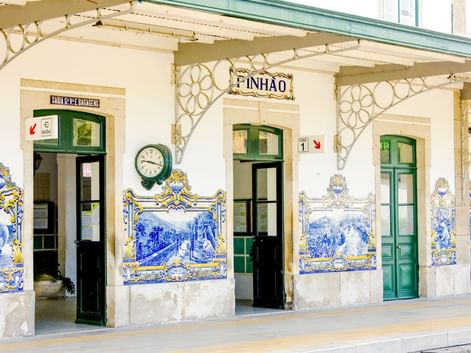 Fassade des Bahnhofs Pinhão mit grünen Türen und Fenstern, geschmückt mit traditionellen portugiesischen blau-weißen Azulejo-Kacheln.