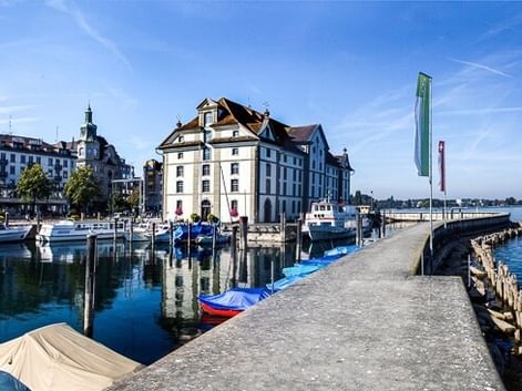 Harbor of Rorschach with historic white buildings, boats moored at the pier, and Lake Constance under blue sky.
