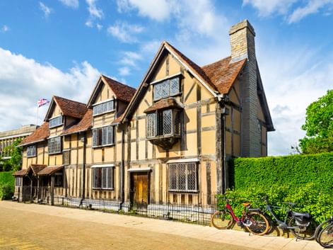 Historisches Tudor-Fachwerkhaus mit cremefarbenen Wänden und dunklen Balken in Stratford-upon-Avon, William Shakespeares Geburtshaus. Fahrräder davor.