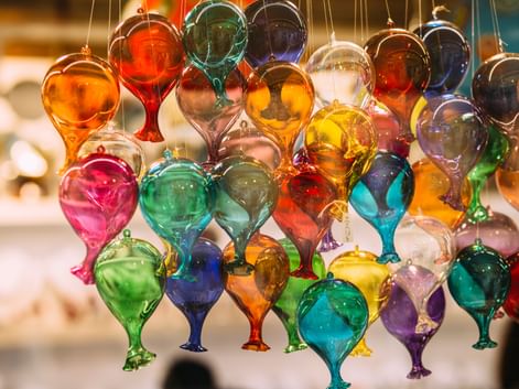 Hängende Ausstellung bunter Muranoglas-Ornamente in Tropfenform mit leuchtenden roten, blauen, grünen, gelben und violetten Farbtönen in Venedig.